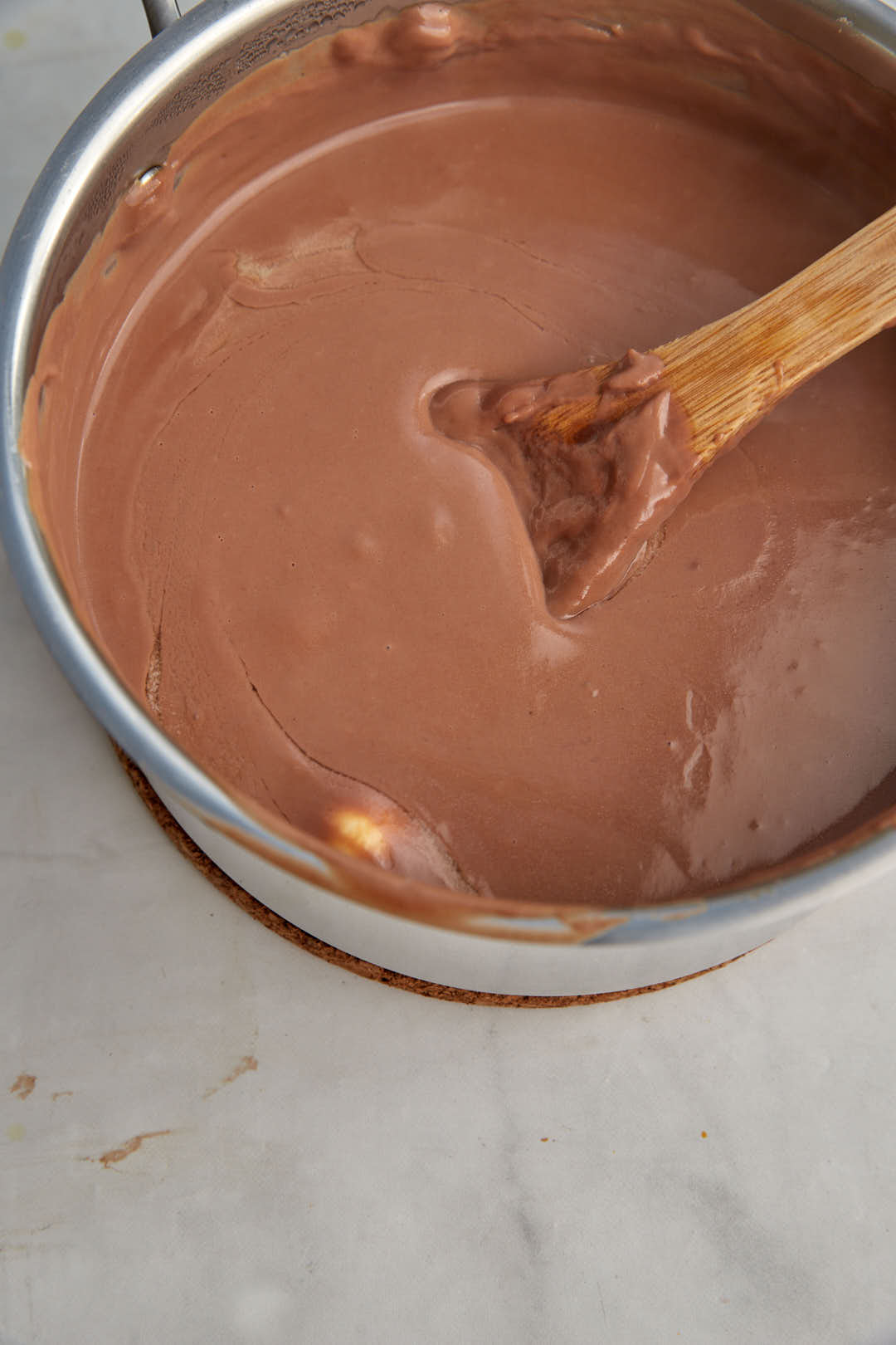 chocolate pudding after cooking in a saucepan with a wooden spoon.