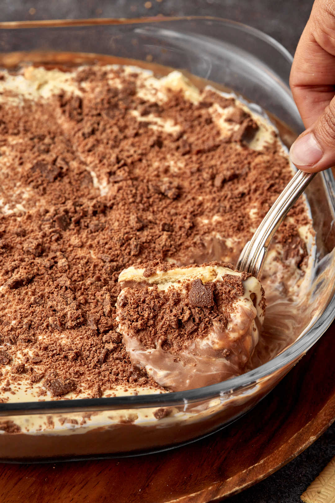 a hand scooping some chocolate pudding out of the serving dish.