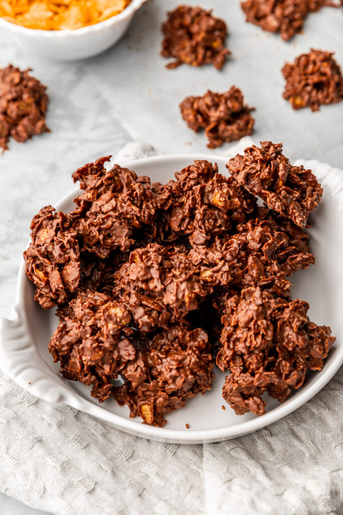 chocolate cornflake clusters in a white dish on a kitchen towel.