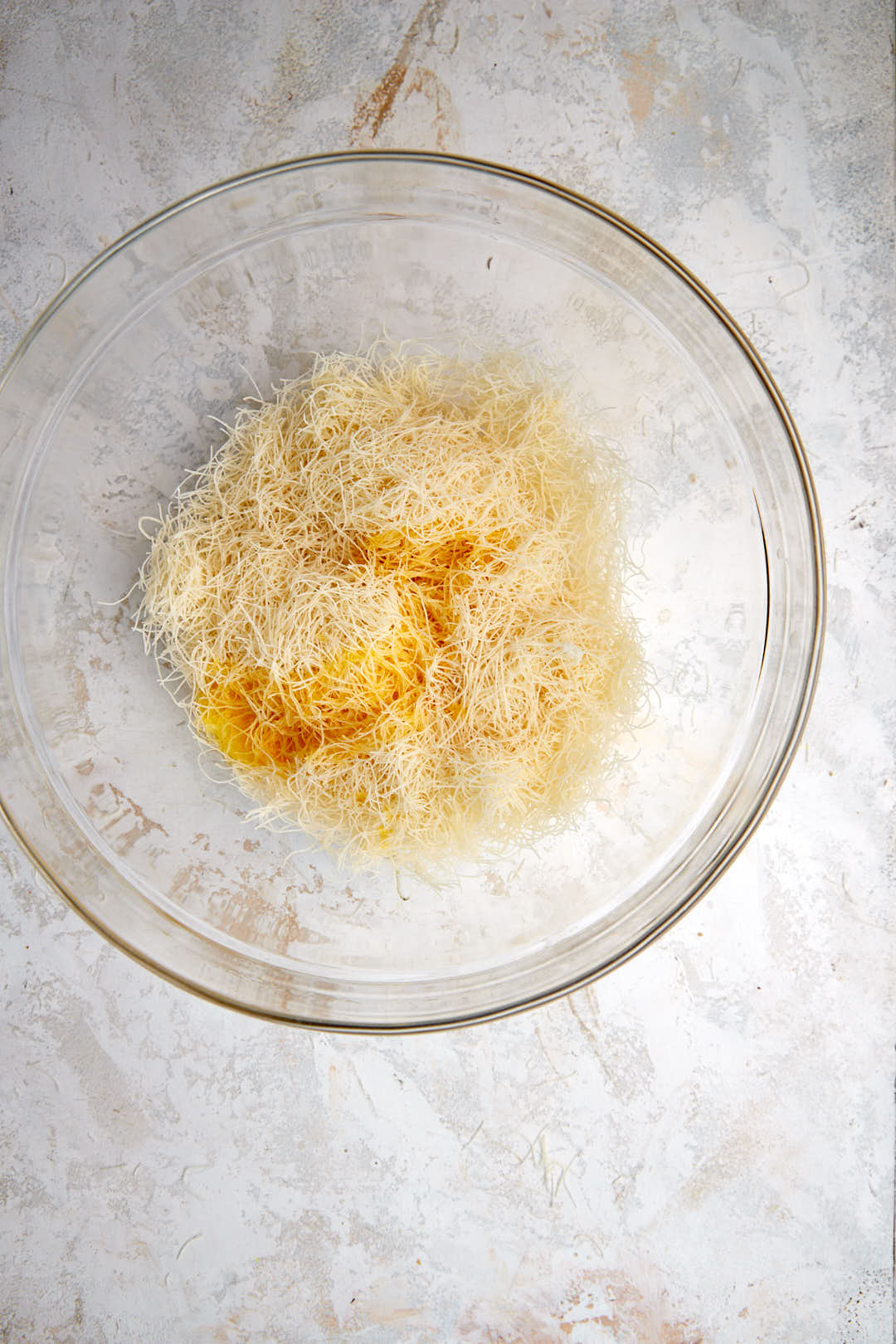 Add the kunafa pieces in a glass bowl with melted butter.