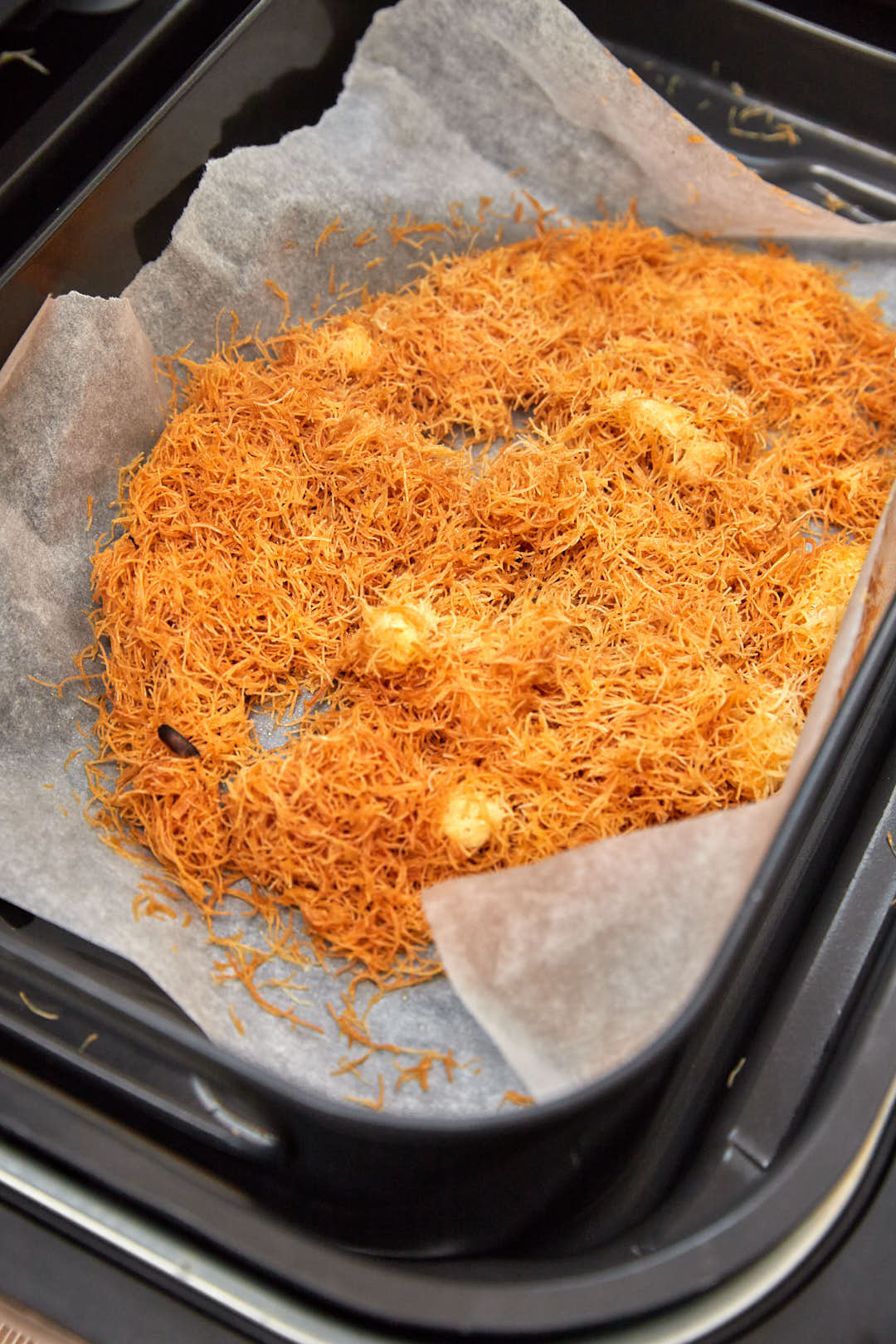 kunafa in air fryer basket after being fried to golden brown.