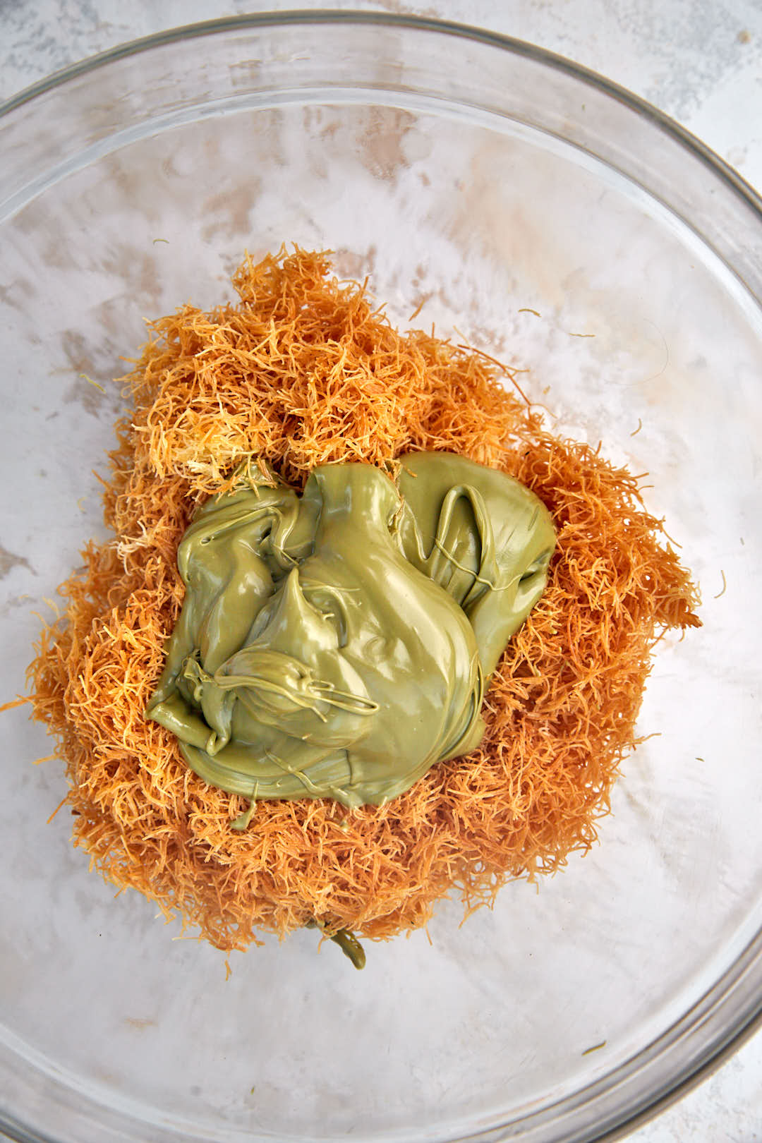 pistachio spread with toasted kunafa in a glass bowl.