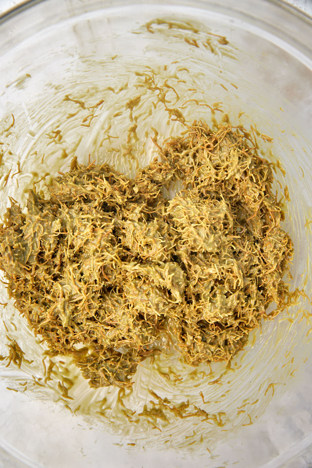 pistacho spread and kunafa mixed together in a bowl.