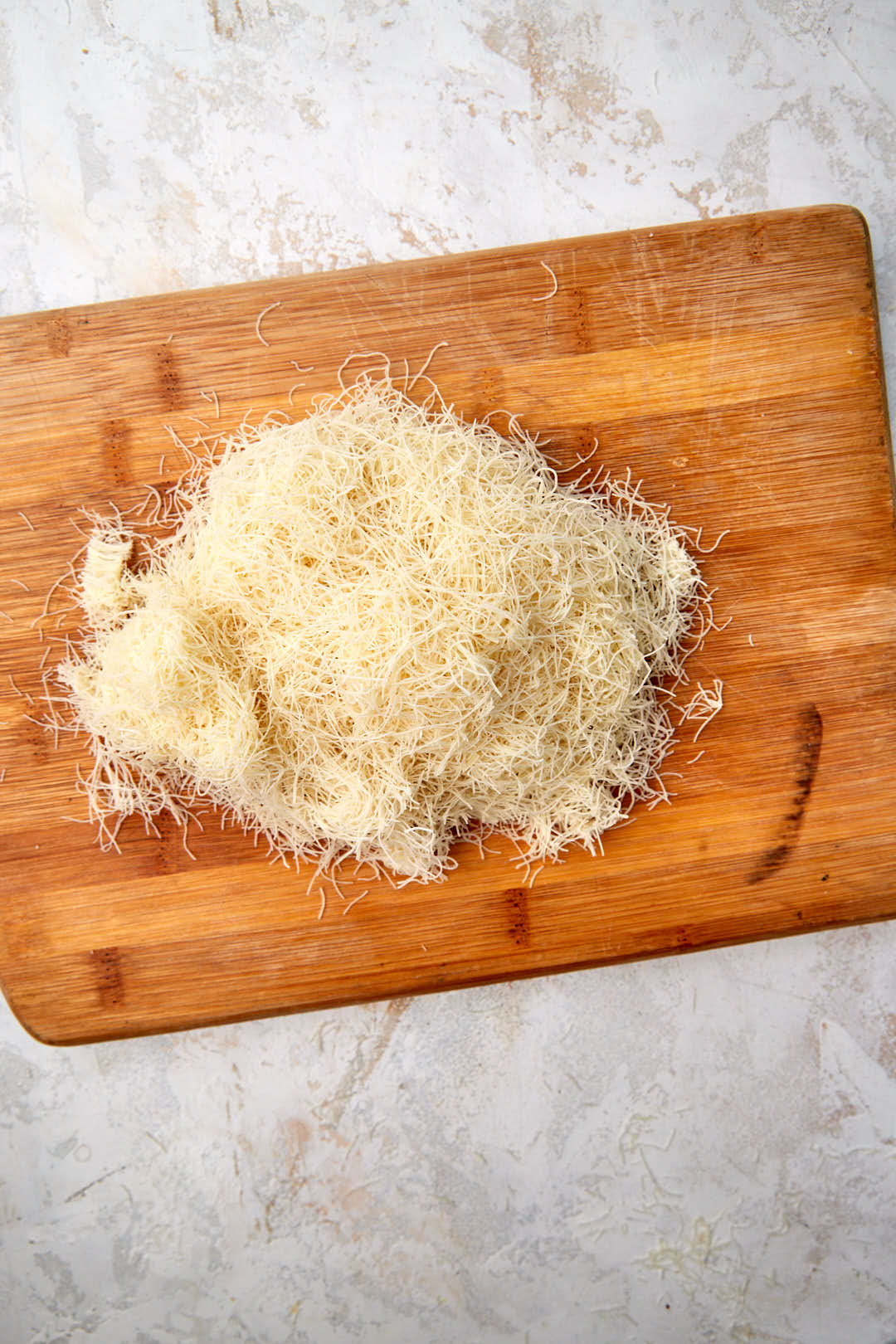 kunafa on a chopping board being chopped into small pieces