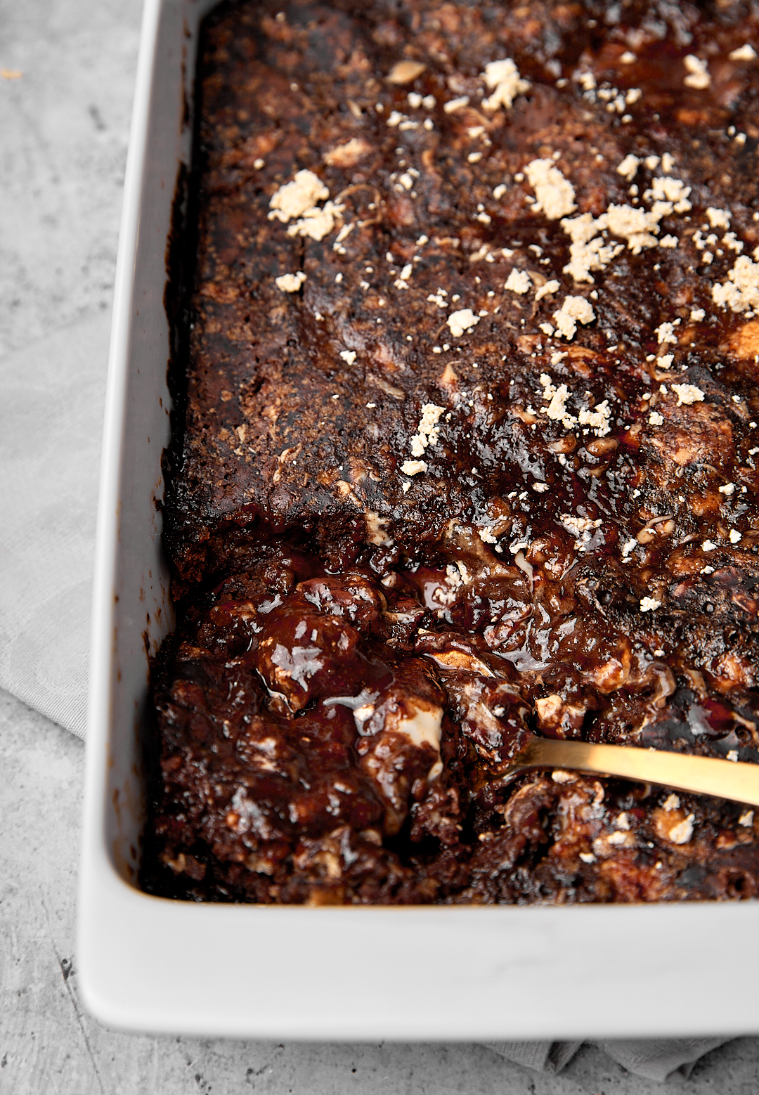 a big spoon being taken out of a chocolate halva self saucing cake.