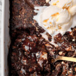 chocolate halva cake with a scoop of vanilla ice cream and a golden spoon taking a big scoop out.