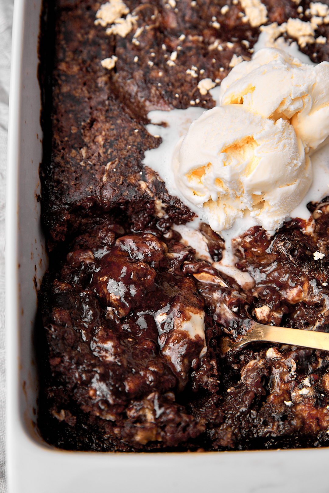 chocolate halva cake with a scoop of vanilla ice cream and a golden spoon taking a big scoop out.