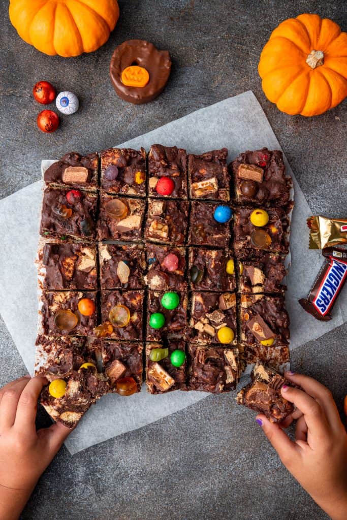 two hands grabbing for chocolate tiffin pieces