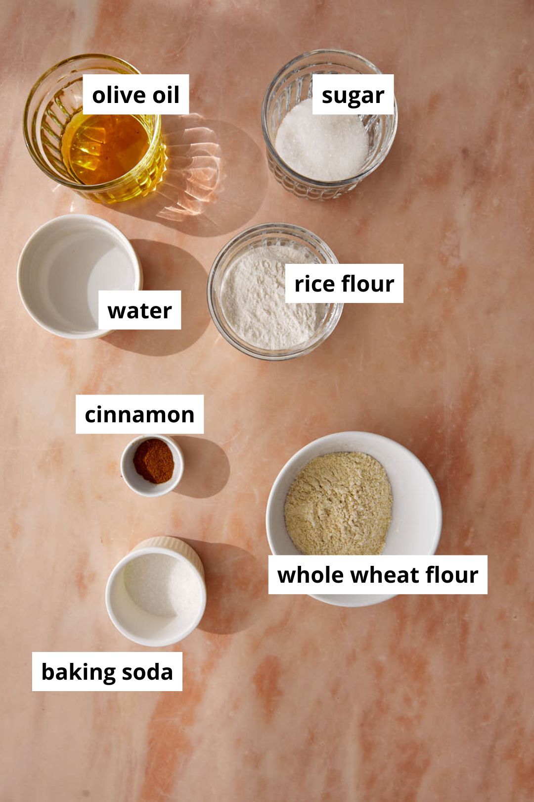 Ingredients needed to make healthy homemade cinnamon toast crunch on a pink background.