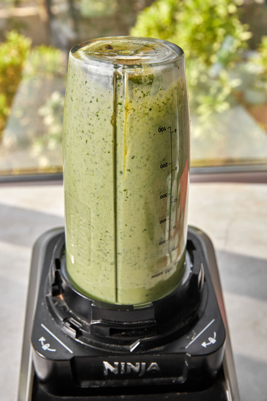 blended green creamy salad dressing in ninja bullet blender capsule.