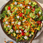assembled corn and arugula salad on large serving dish.