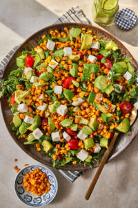 assembled corn and arugula salad on large serving dish.