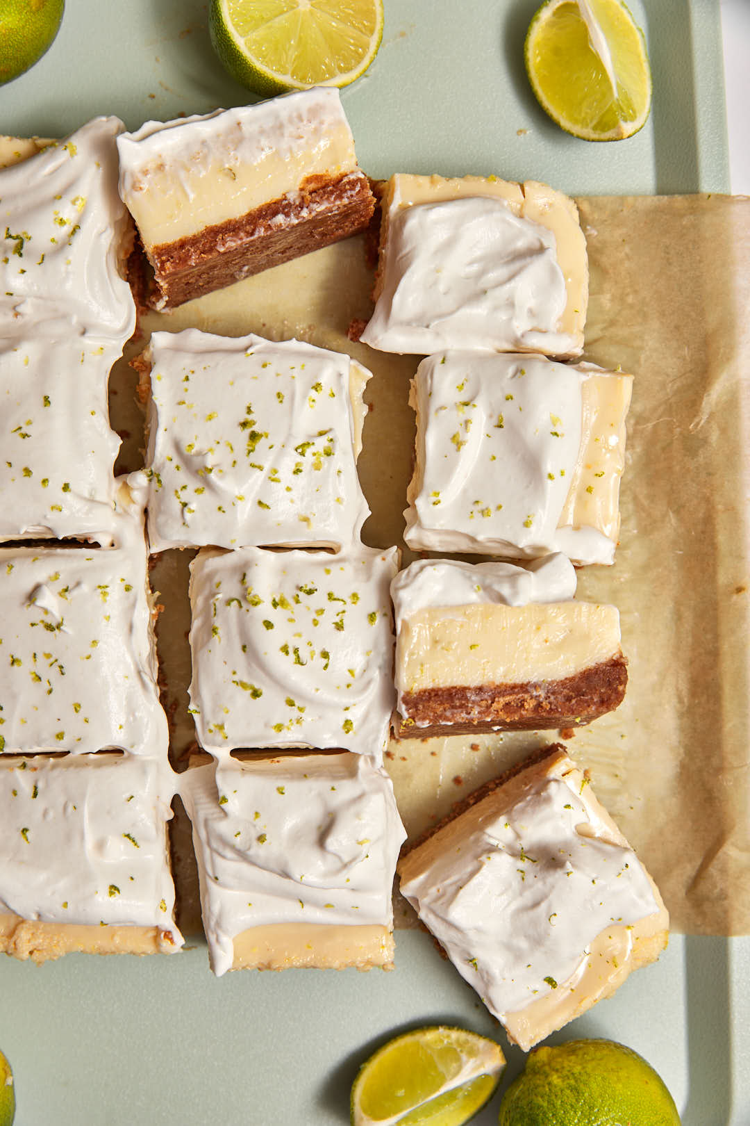 key lime pie bars on brown parchment paper with some bars on their sides tos how the creamy filling.