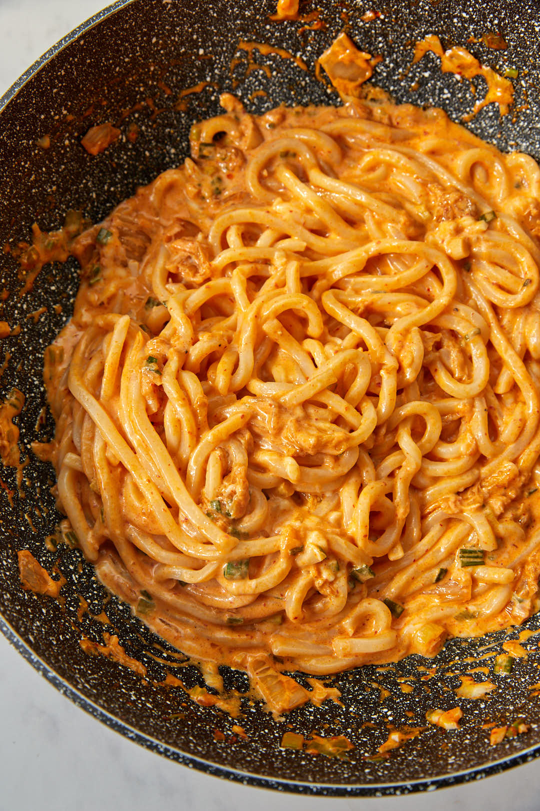 creamy kimchi udon noodles in a large skillet.