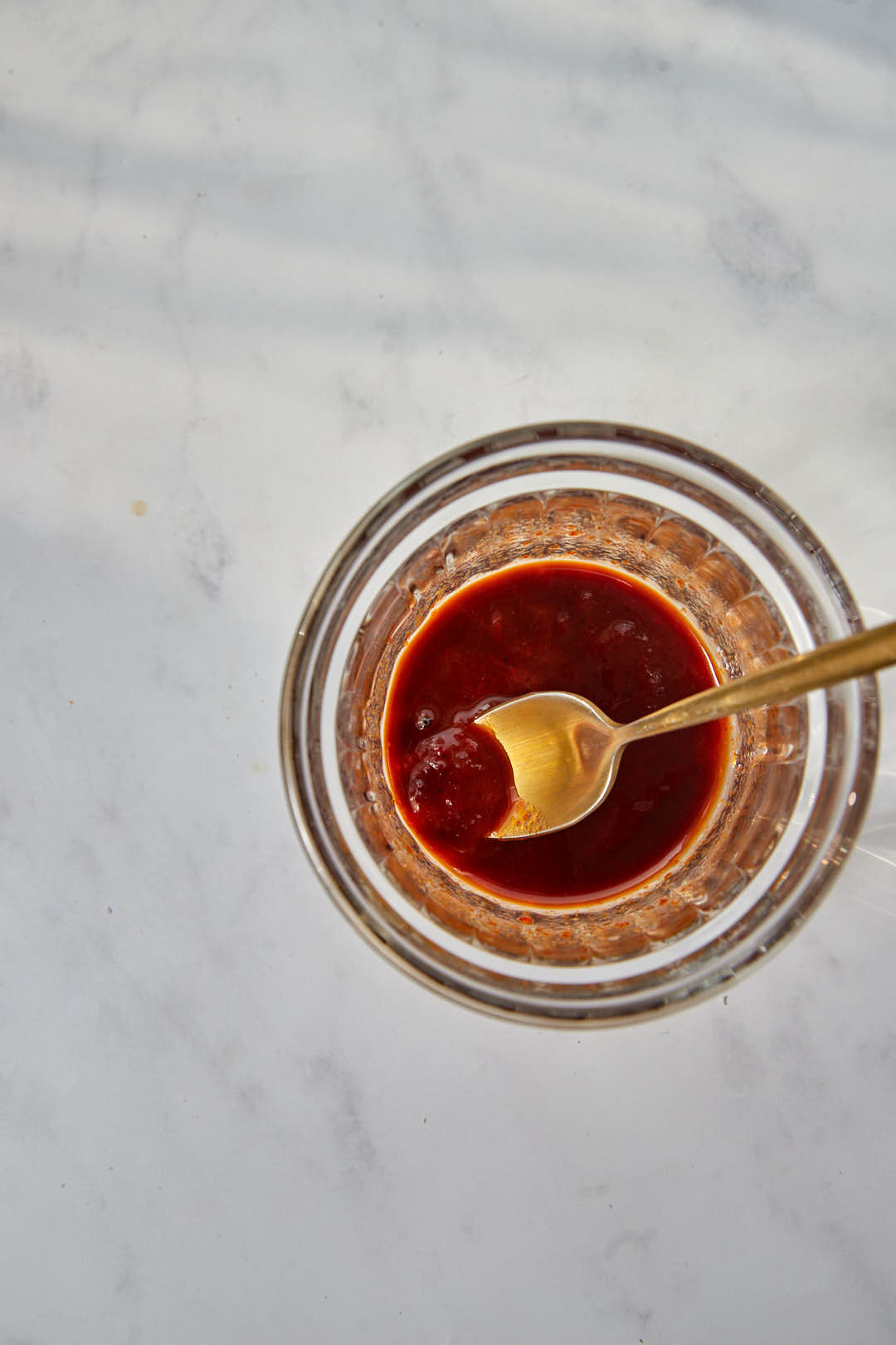 gochujang, sugar, and soy sauce mixed together with a small gold spoon in a small glass ramekin.