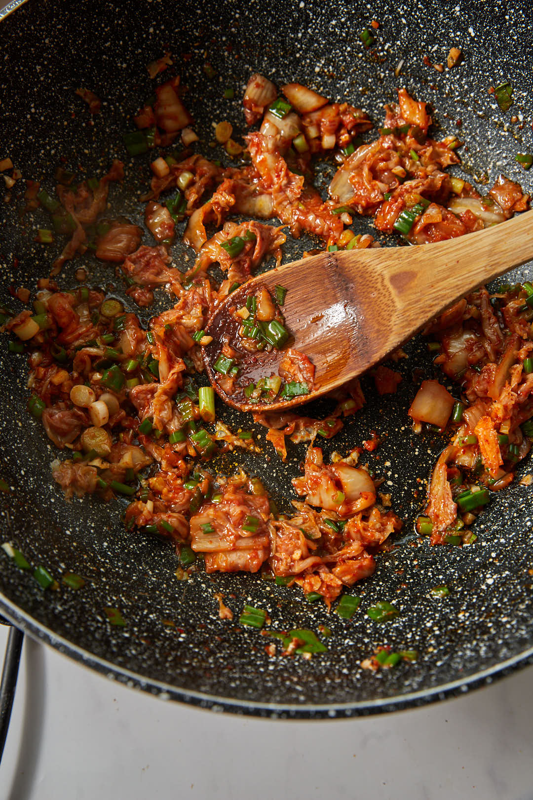 kimchi and green onions stirred in a large skillet.