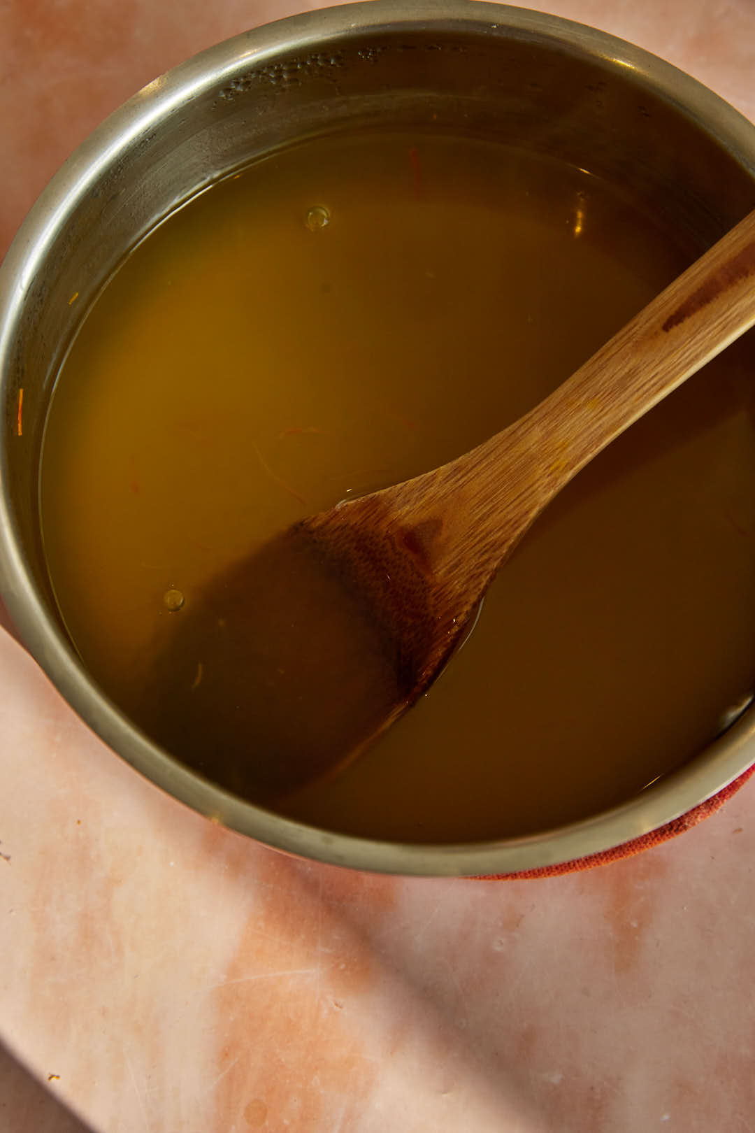 sago and water in a metal pot with a wooden spoon in it.