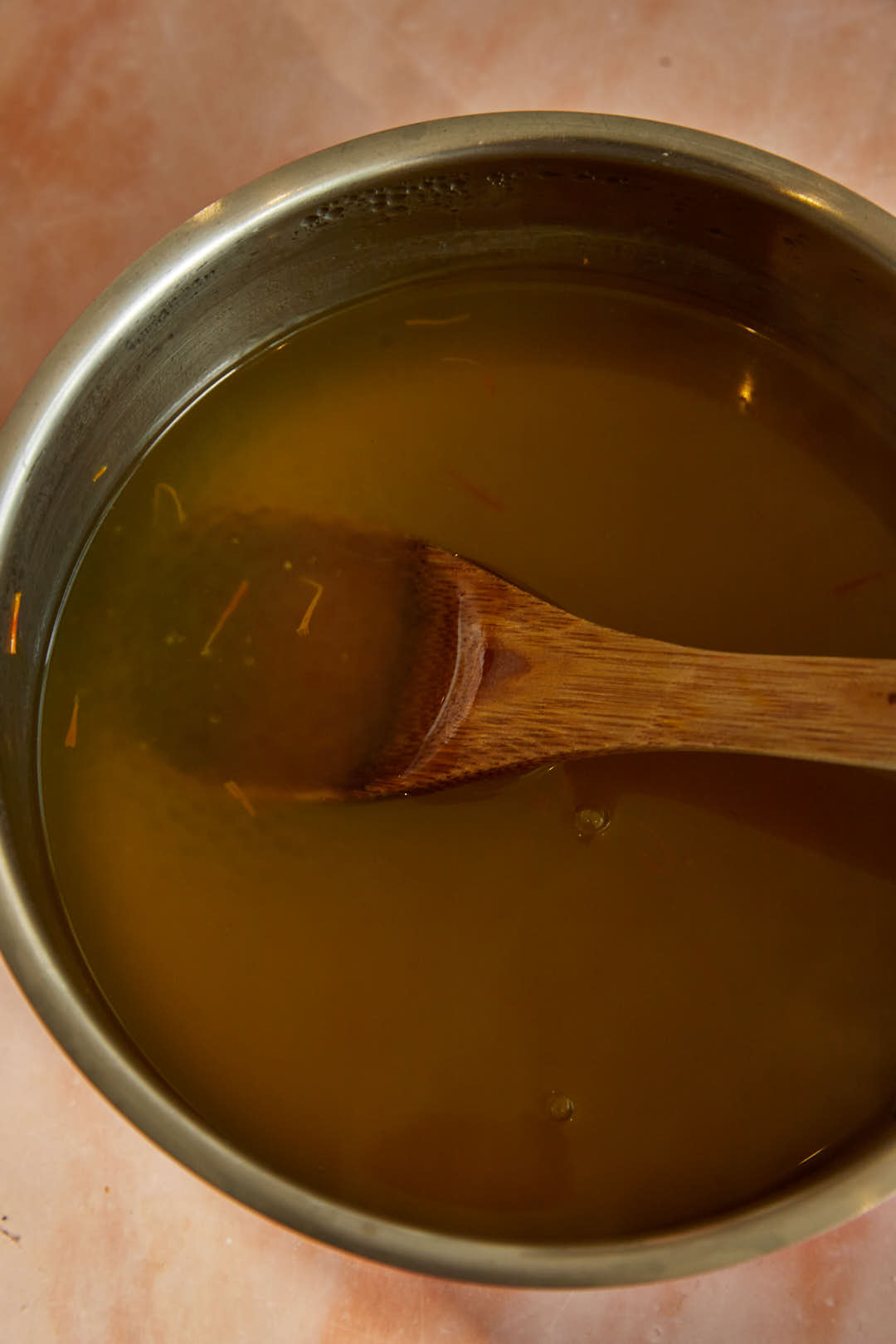 Sago being cooked in saffron water in a metal pot.