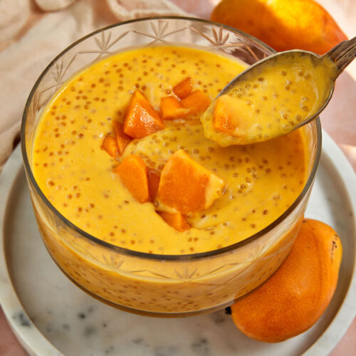 mango sago being spooned out of a large glass seving dish