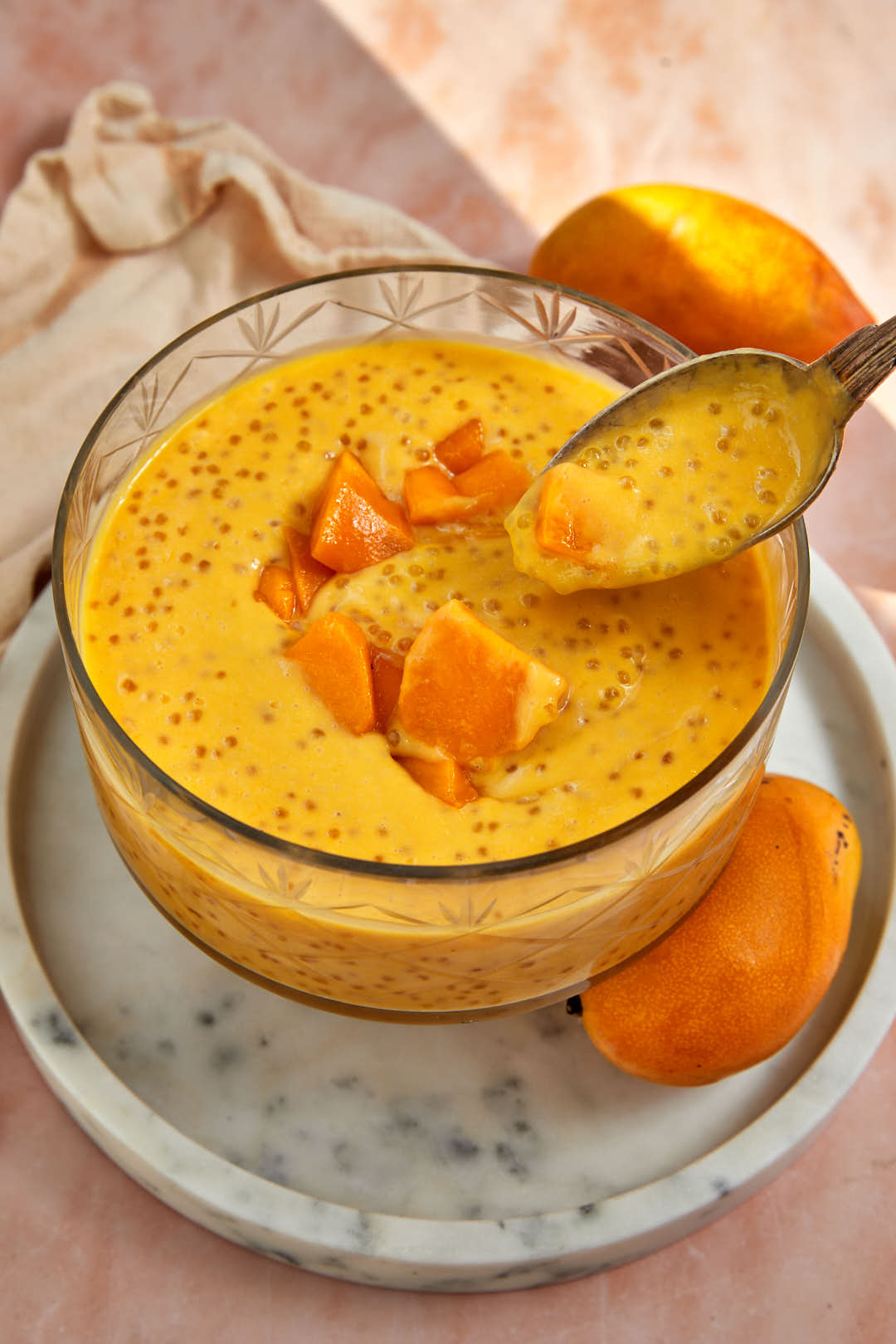 mango sago being spooned out of a large glass seving dish