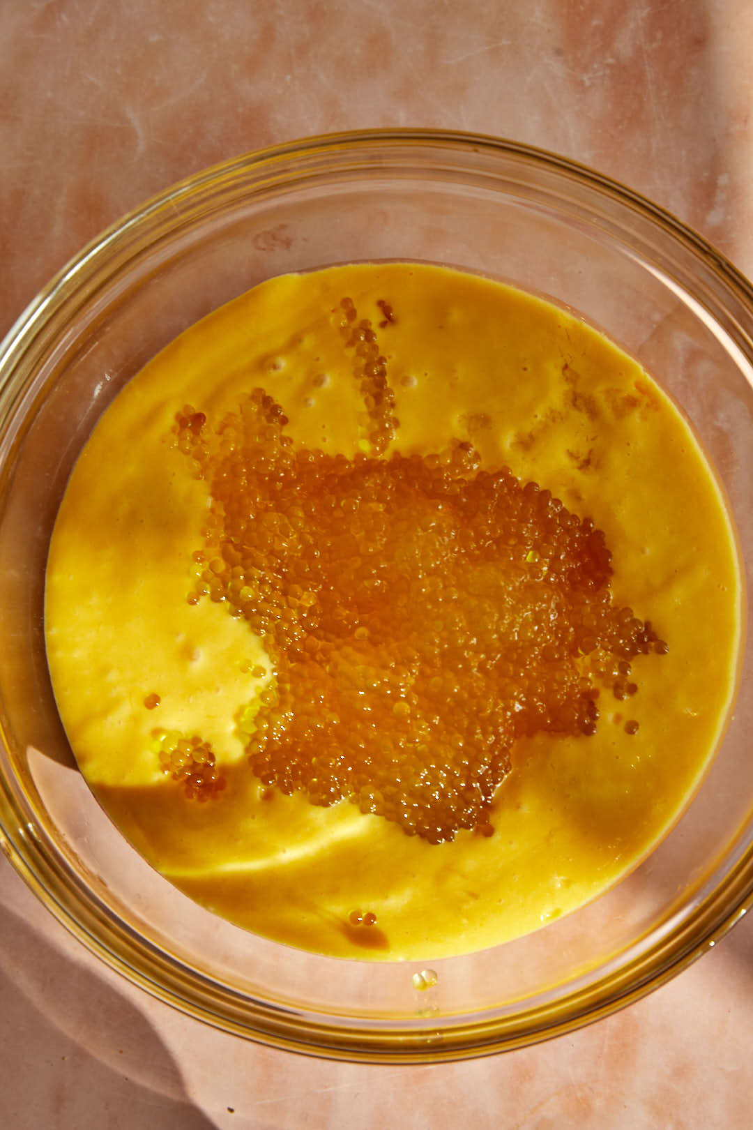 cooked sago added to mango puree in a glass bowl.