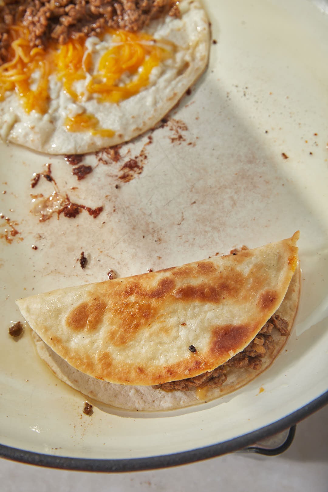 one taco folded in half in a large skillet.
