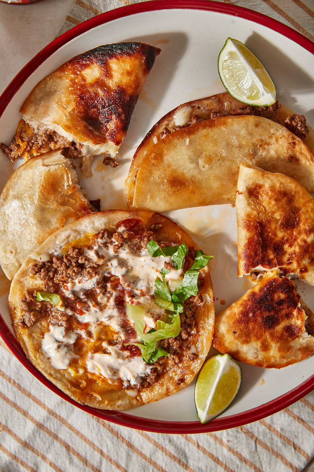 close up photo of crispy beef tacos on a white plate with a lime slice.