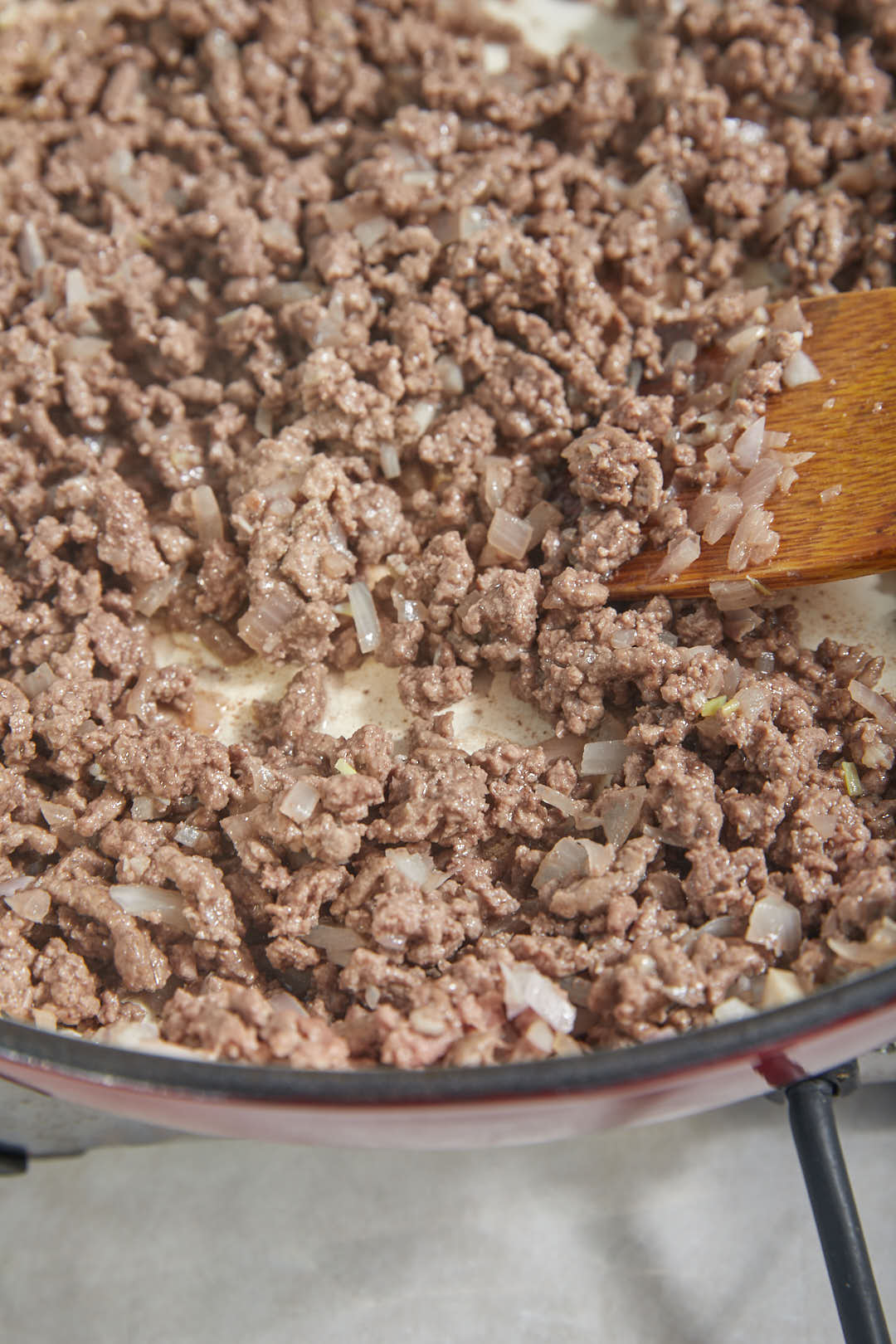 ground beef cooked in a skillet with a wooden spoon.
