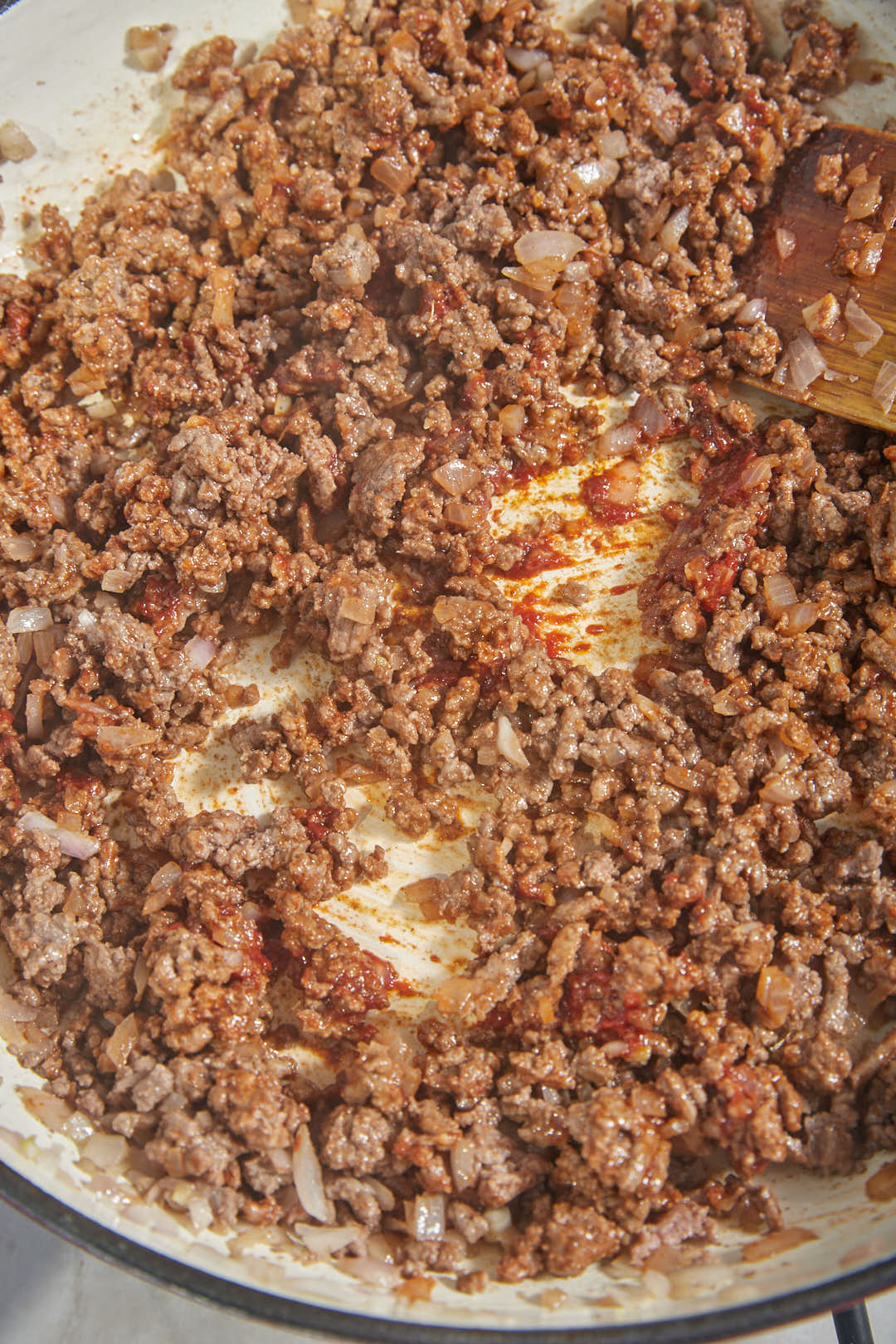 ground beef and tomato paste and spices and red onion in a skillet.