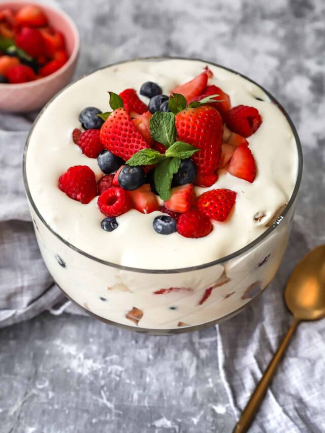 berry cream trifle in glass bowl on gray background.