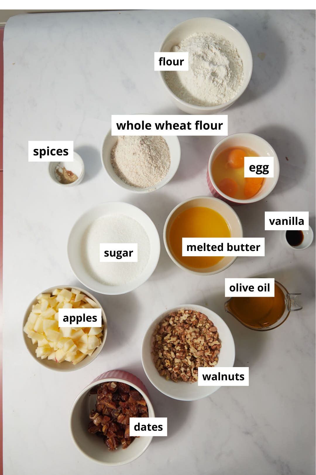 ingredients needed to make an apple date cake on a white background.