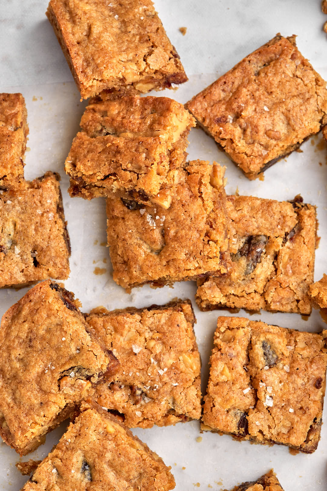 date blondies cut into squares and stacked on top of each other on parchment paper