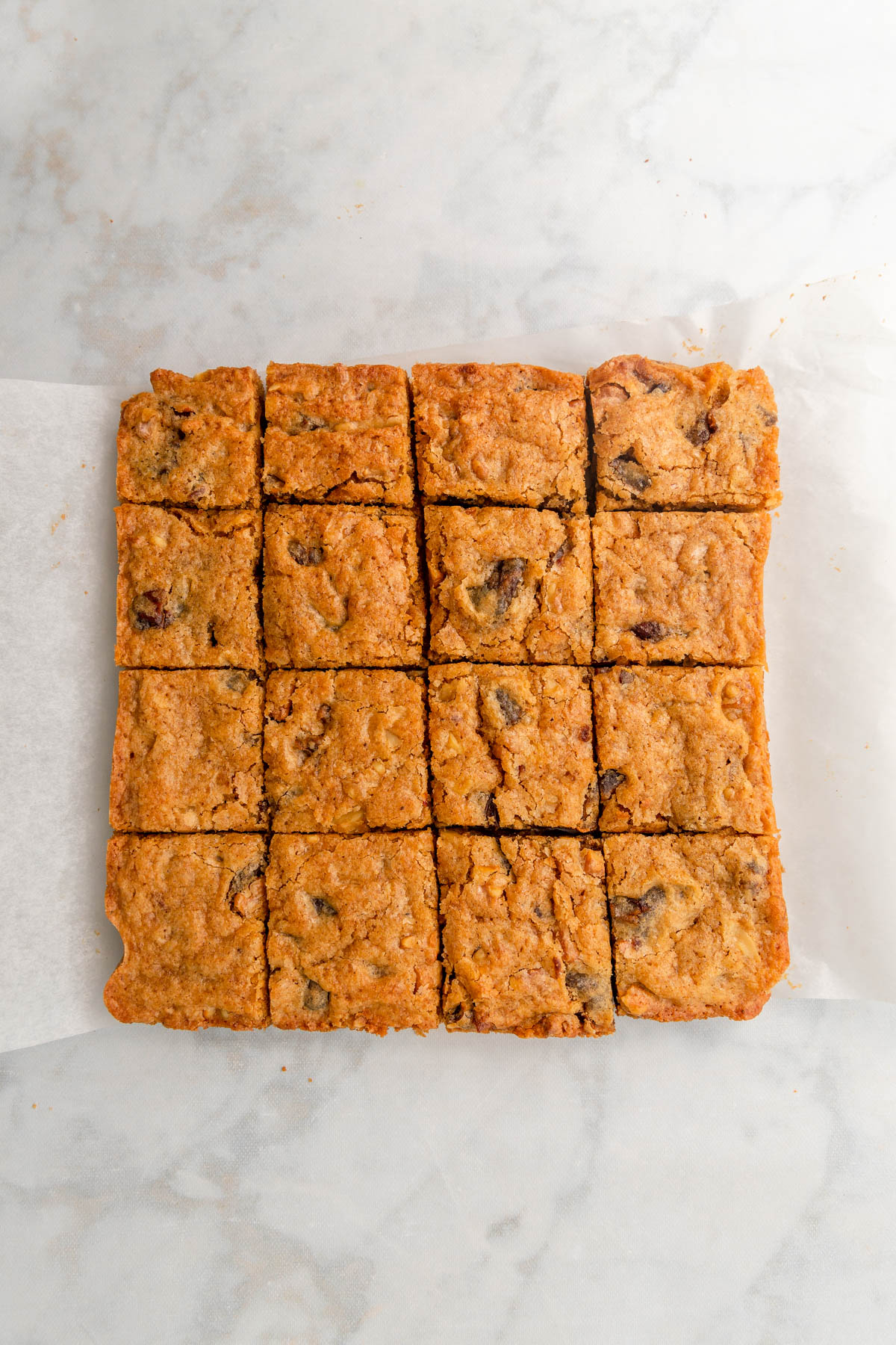 Blondies cut into squares on white marble background.
