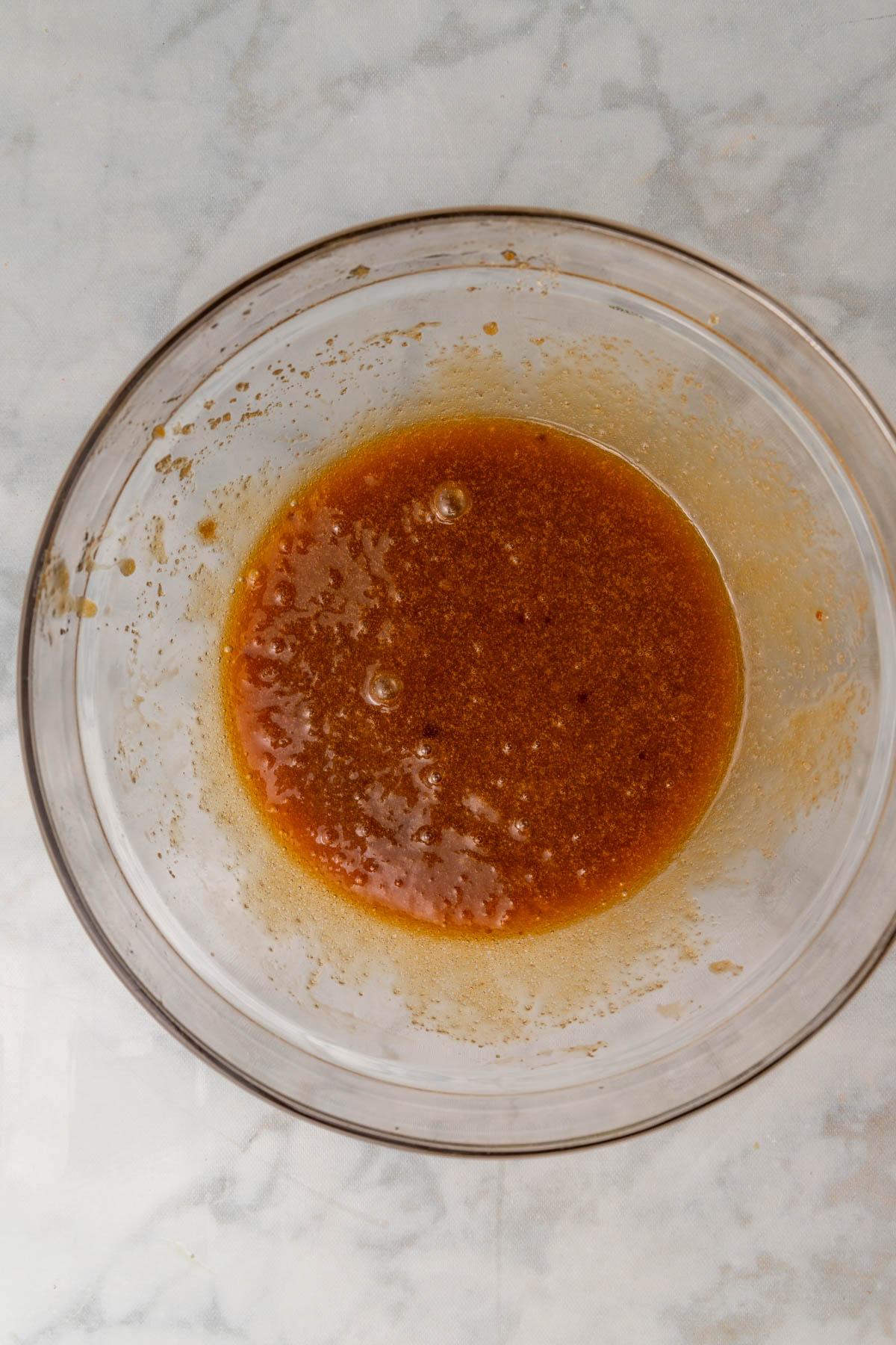 egg yolks mixed in with melted butter and brown sugar in a glass bowl.