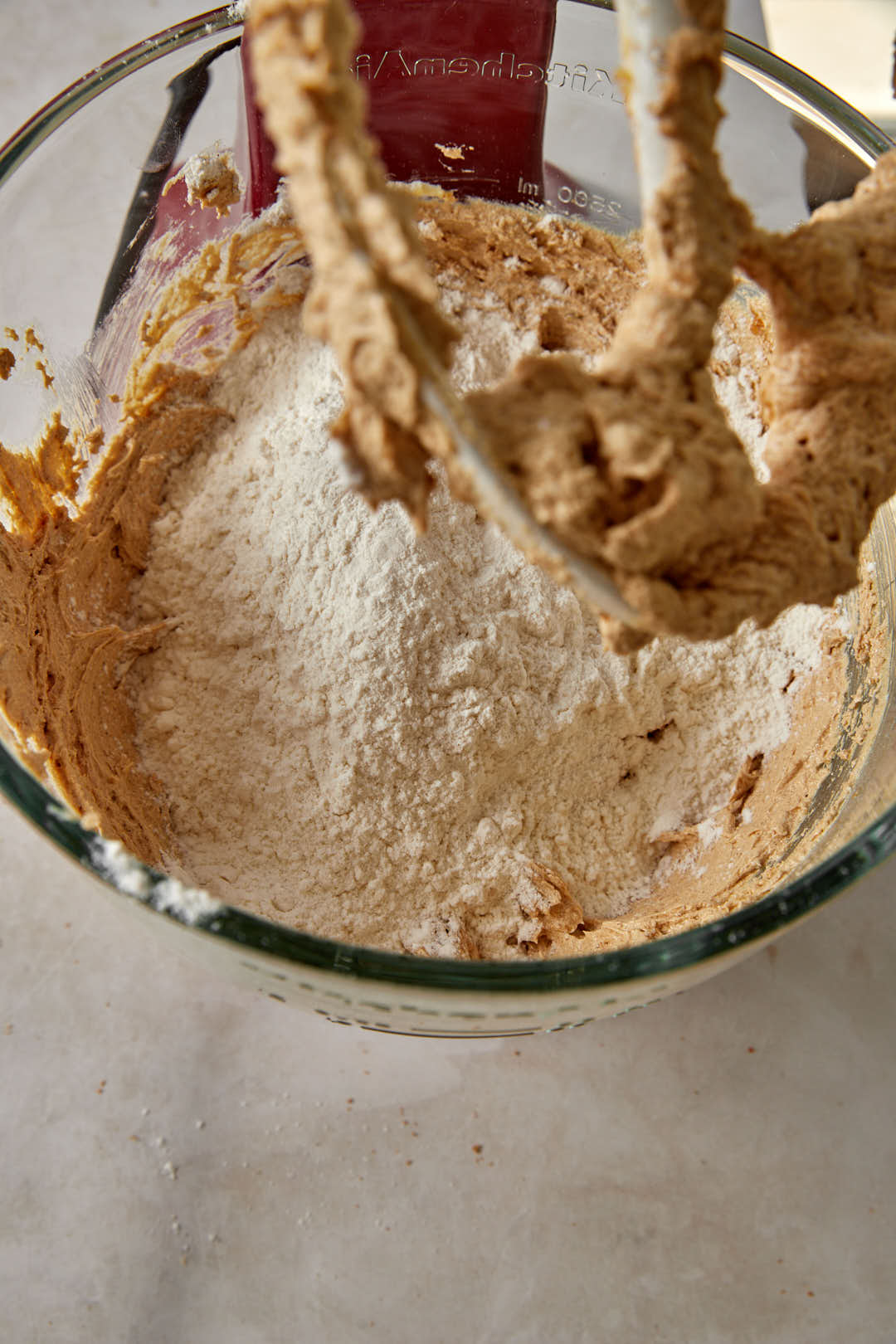 flour added to the butter and sugar for cookie dough in a stand mixer.