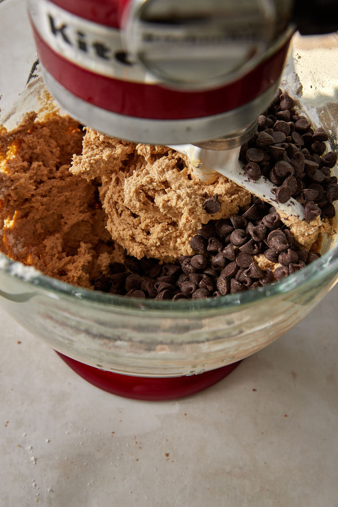 Chocolate chips added to cookie dough in a stand mixer.