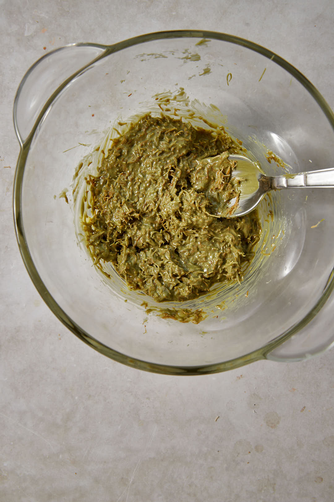 Mixture of pistachio cream and toasted kunafa in a glass bowl.