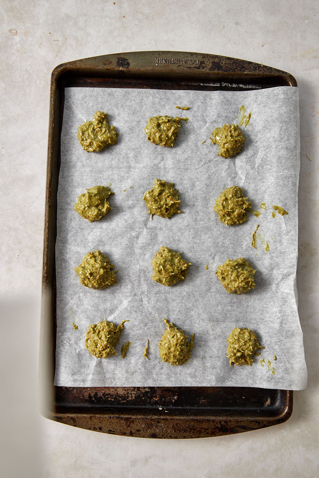 heaped teaspoons of pistachio kunafa on parchment paper lined baking sheet.