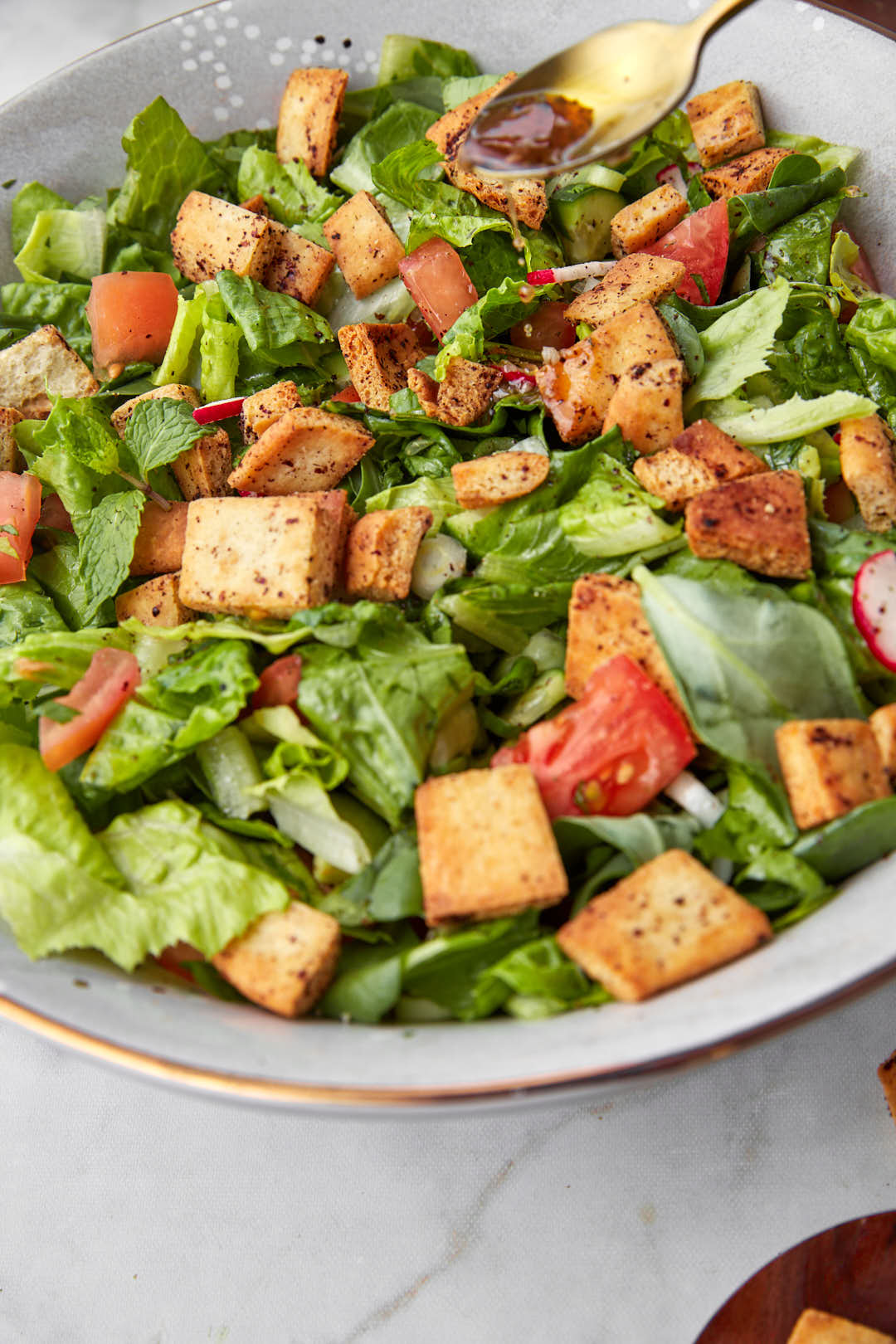 salad dressing being drizzled onto fattouch.