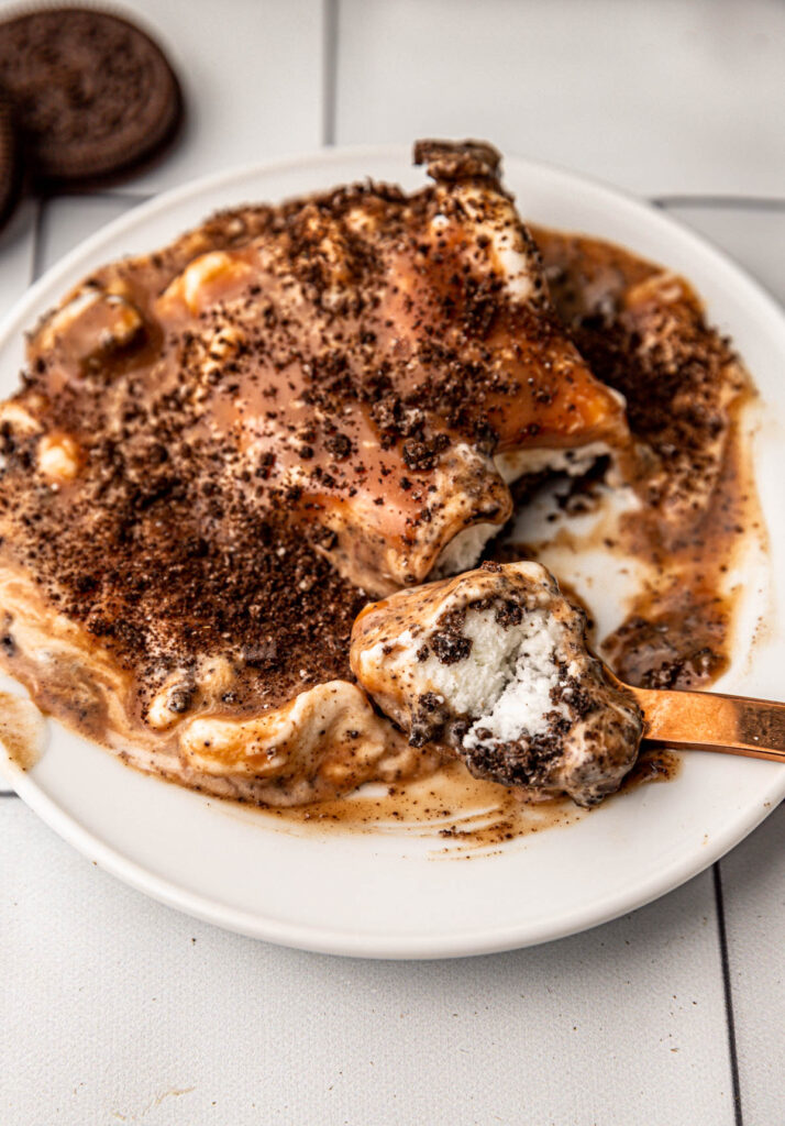 spoon taking a bit eof oreo ice cream with chocolate topping.