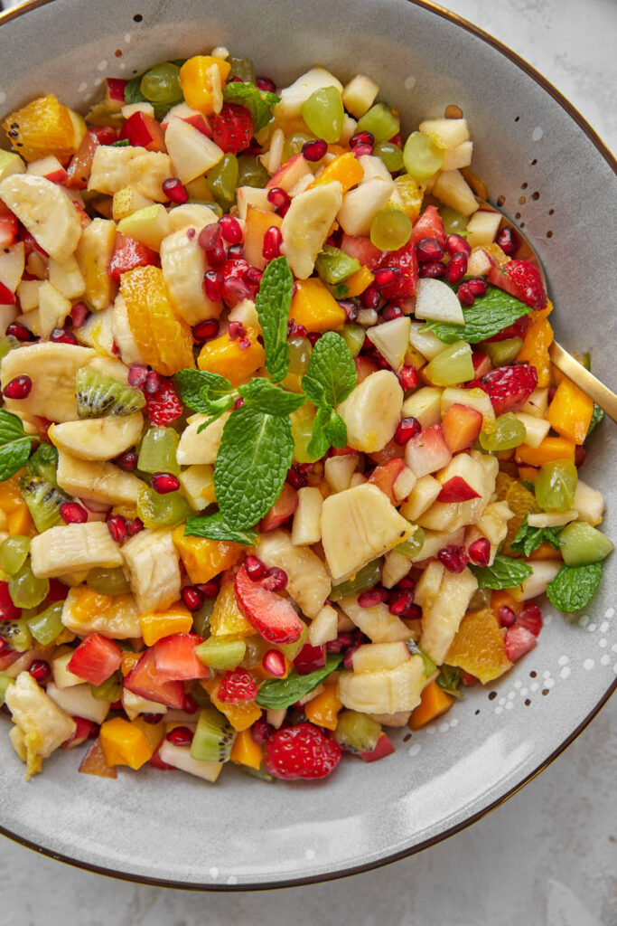fruit salad in a grey bowl with mint leaves.
