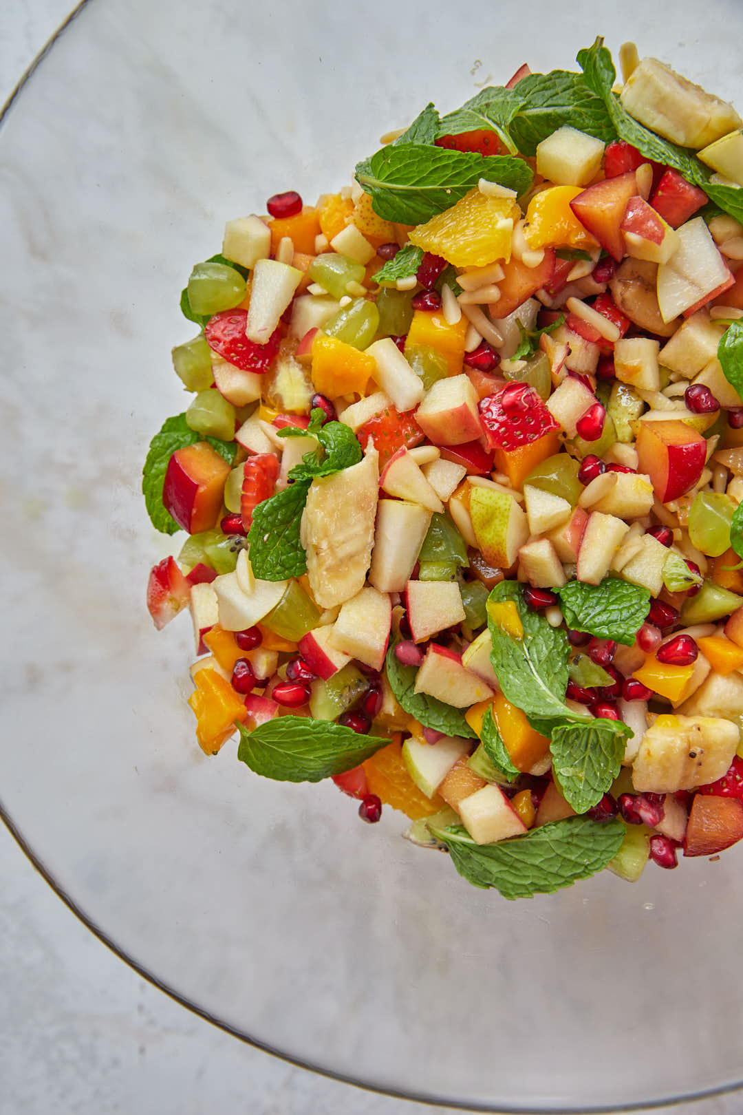 middle eastern fruit salad with mint leaves in a glass bowl.