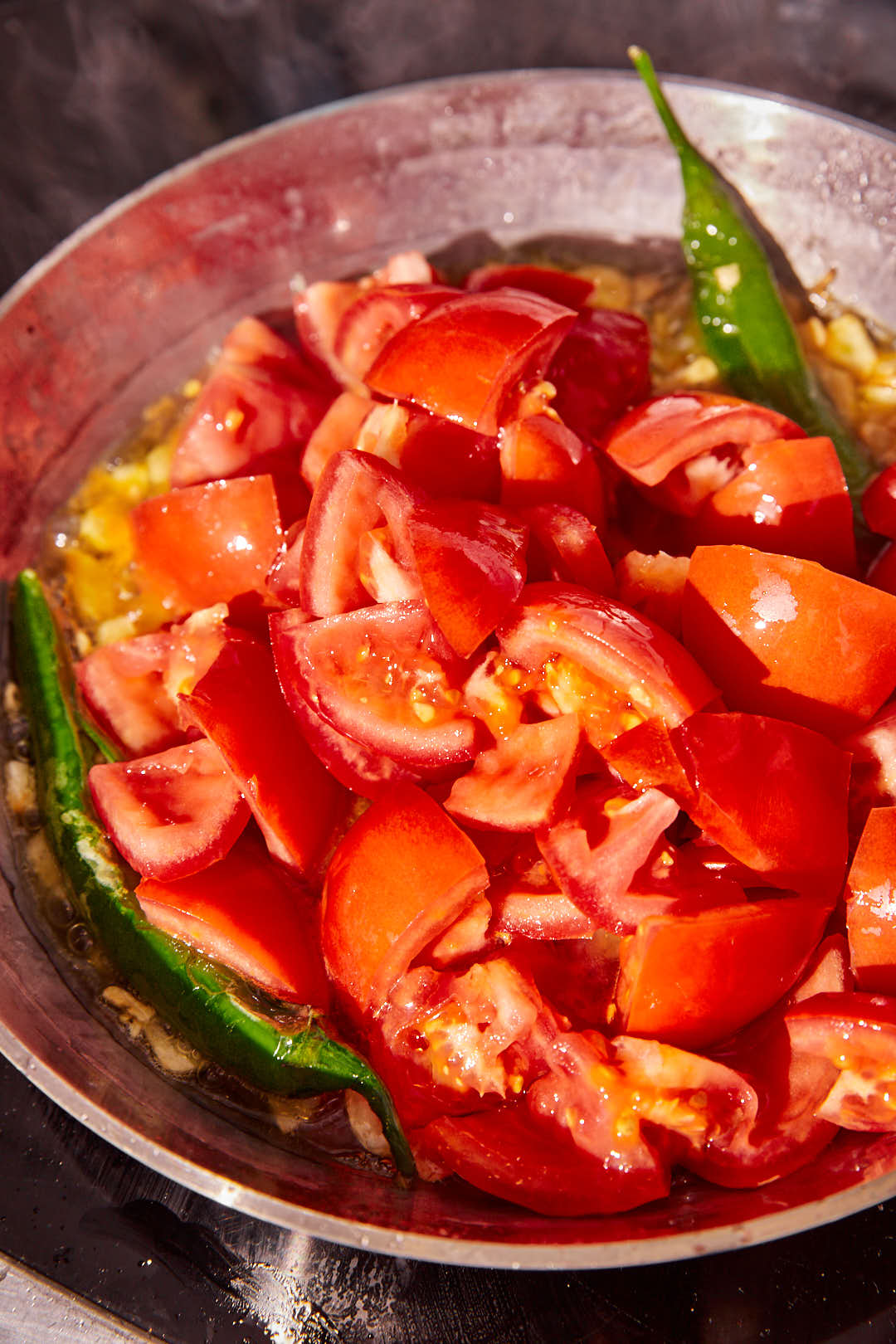 big chunks of tomatoes with green chili peppers in a skillet.