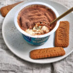 tiramisu greek yogurt on a white plate with extra lotus biscuits on the side.