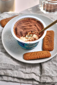 tiramisu greek yogurt on a white plate with extra lotus biscuits on the side.