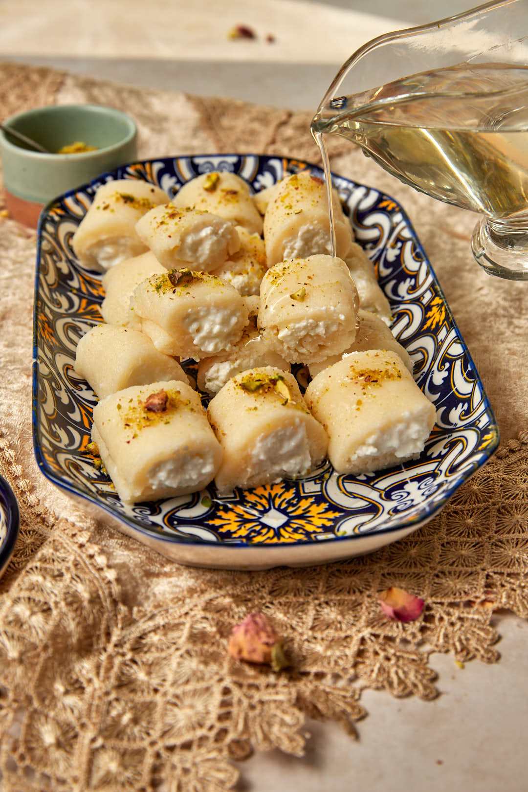 sugar syrup being drizzled onto a platter of halawet el jibn.
