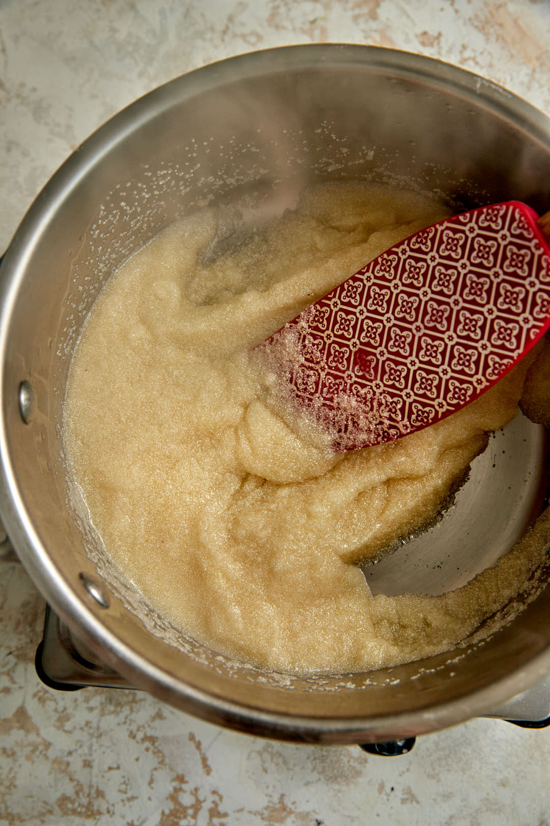 semolina being stirred into a sugar water mixture in a saucepan.