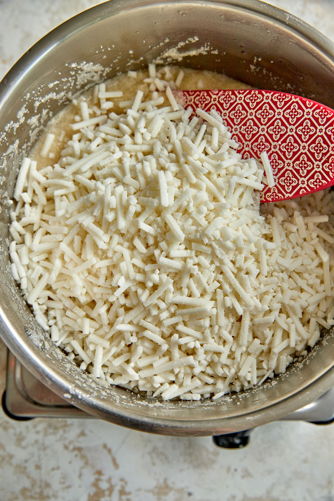 shredded mozzarella cheese added to semolina mix in a saucepan.