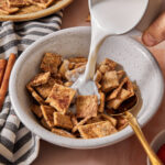 milk being poured into a bowl of healthy homemade cinnamon toast crunch cereal.