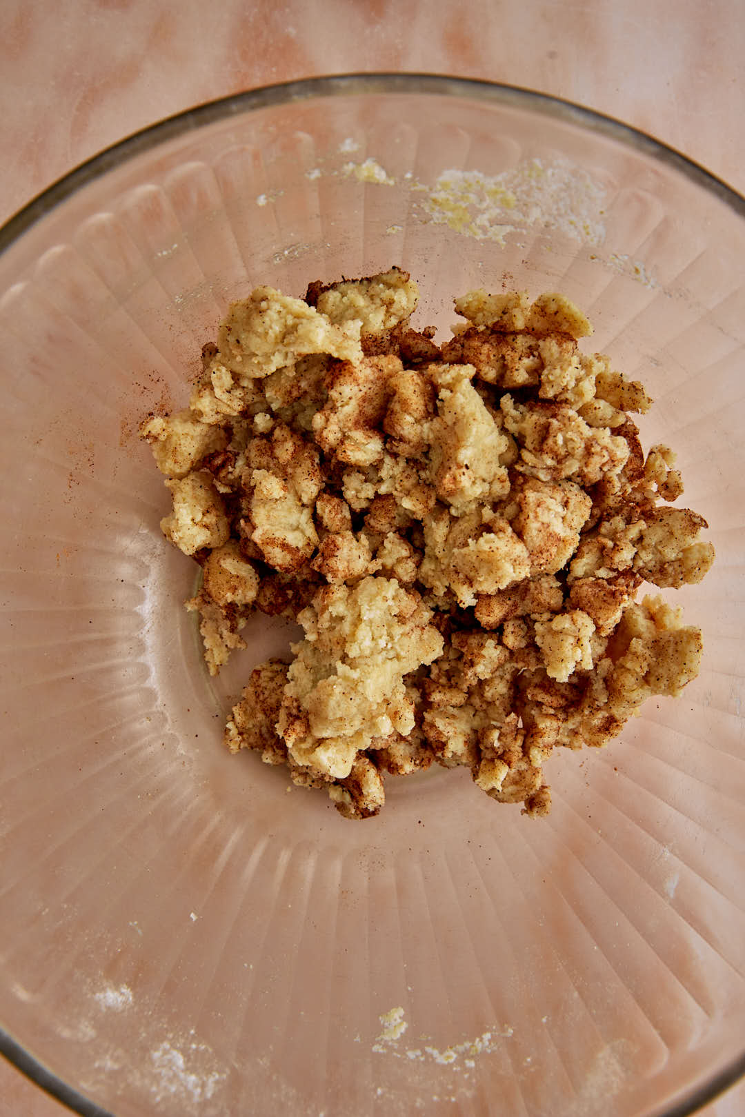 Cinnamon sprinkled on cereal dough in glass bowl.